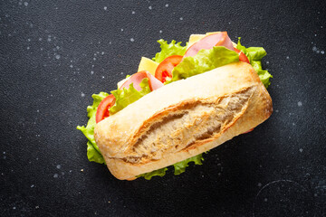 Canvas Print - Ciabatta sandwich with lettuce, cheese, tomatoes and ham on black background. Fast food, snack or lunch. Top view with copy space.