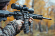 © CozyDigital - Soldier in camouflage and gear aims an assault rifle with scope. Side view.