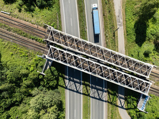 Aerial view from the drone of the railway bridge over the expressway. Freight train on metal iron bridge. Tracks and an iron railway bridge against the background of green fields.