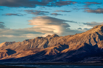 Wall Mural - Sunrise over rocky mountain range on dry field in autumn