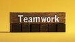 © MakoPoko - The word 'Teamwork' spelled out in white text on dark wooden blocks, set against a plain yellow background, in a 3D rendering.