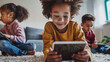 © Chatchanan - Children in an apartment, happily typing on a tablet and interacting with social media while sitting on the floor.