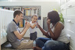 © Anna Berkut/Stocksy - multiracial family, happy parents playing with baby child at home