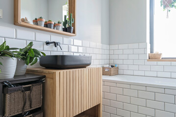 Wall Mural - Modern bathroom sink in industrial interior with white tile on the wall and wooden mirror and black ceramic wash basin.