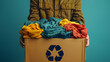 © Ekaterina - A person holds a box filled with colorful clothes for recycling, emphasizing sustainable practices and environmental responsibility, banner with copy space