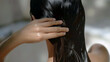 © Andres Mejia - Woman applying hair product for healthy and shiny hair