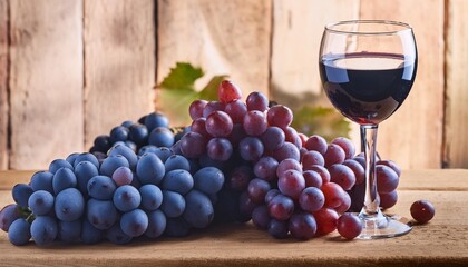 Wall Mural - close up shot of red grapes in a rustic winery setting with a wine glass and a bunch of fresh blue grapes all on a wooden plank providing copy space image