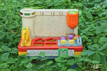 one colored plastic toy model kitchen stands in green vegetation in summer garden outside