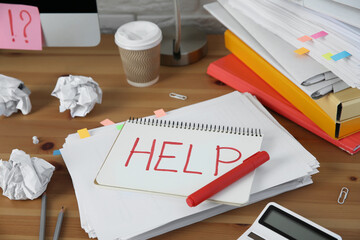 Notebook with word Help and stationery on wooden table at workplace