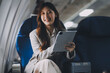 © ARMMY PICCA - Joyful asian woman sits in the airplane and using tablet while go to travel