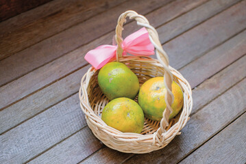 Yellow green orange fruits in basket isolated on wooden background