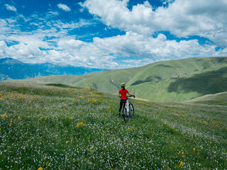 Wall Mural - woman riding mountain bike on beautiful flowering grassland mountain top