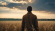 © Den Boro Day - Back view of a man standing in the middle of the field and looking at the sky.