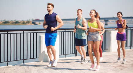 Canvas Print - Group of young sporty people running together outdoors