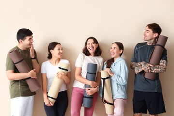 Poster - Group of sporty young people with yoga mats near beige wall