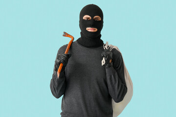 Wall Mural - Male thief with bag and crowbar on blue background