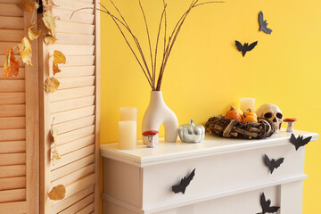 Wall Mural - Vase with tree branches, skull, candles and Halloween pumpkins on fireplace in room