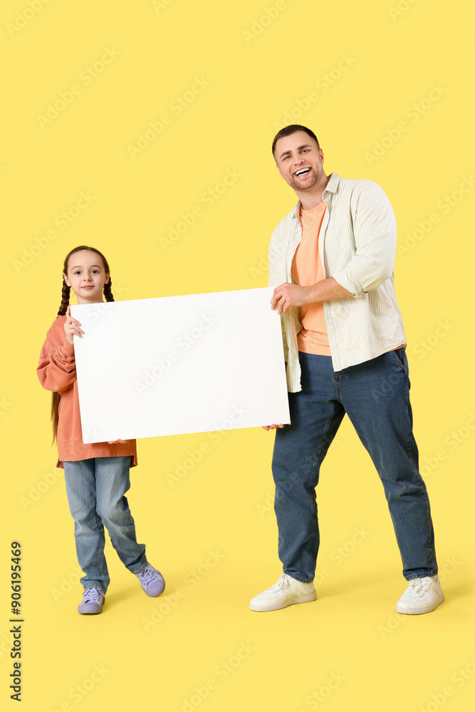 Father and his daughter holding blank poster on yellow background