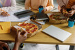 © Oleksii Syrotkin/Stocksy - Eating pizza at lunch with colleagues. Drinking coffee. Office workers