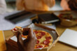 © Oleksii Syrotkin/Stocksy - Pizza box on office table eating at lunch. Crop hand Holding junk food