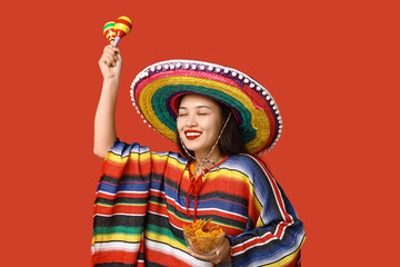 Sticker - Portrait of young woman with colorful poncho, sombrero, maracas and tortilla chips on red background. National Tortilla Chip Day celebration