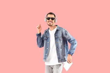 Canvas Print - Young bearded man in headphones with tablet computer listening to music on pink background