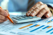 © Poramet - Close-up of accountant using calculator while examining report