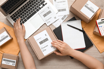 Wall Mural - Female postal worker with parcel using laptop on table, top view