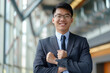 © N. W. - happy young asian businessman in a suit smiling proudly into the camera