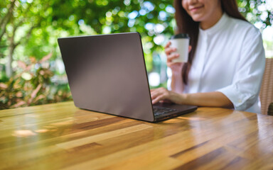 Wall Mural - Closeup image of a young woman working and typing on laptop computer keyboard in the outdoors