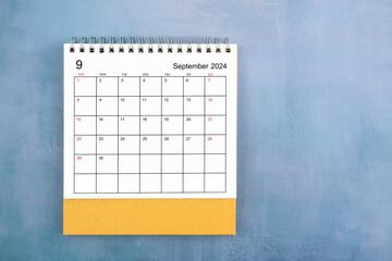 Directly above view of September 2024 desk calendar on blue wooden background.