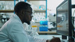 © VK Studio - A scientist in a lab coat working intently at a computer in a laboratory, surrounded by scientific equipment, exemplifying dedication and focus in research.