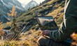 © Nadin Faust - person working on a laptop in an alpine meadow with high-resolution graphics visible, surrounded by mountains and forests, capturing a realistic outdoor work scene