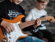 © Teerapon - Two boys playing electric guitar, showcasing their musical talent in a relaxed setting.