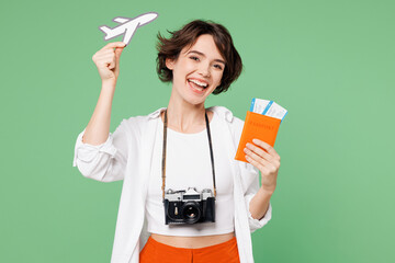 Wall Mural - Traveler happy woman wear casual clothes hold passport ticket show air plane mockup isolated on plain green background. Tourist travel abroad in free spare time rest getaway. Air flight trip concept.