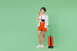 © ViDi Studio - Full body happy fun traveler woman wearing casual clothes hold suitcase bag use mobile cell phone isolated on plain green background. Tourist travel abroad in free time rest. Air flight trip concept.