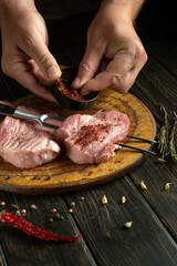 Wall Mural - Meat with spices is prepared before the grill. The chef hands add aromatic seasoning to veal patties.