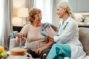 Smiling professional doctor, cardiologist holding pacemaker, showing to senior patient