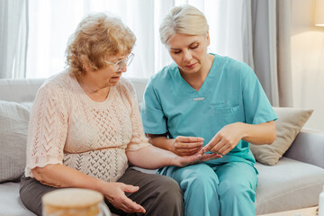 Nurse giving medical pills to elderly woman on sofa