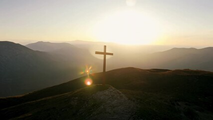 Poster - A wooden cross is on a hillside with a beautiful sunset in the background. Concept of peace and serenity, as the cross stands as a symbol of faith and hope in the midst of a picturesque landscape.