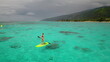 © Anastasia Pro - Young woman is enjoying a sunny day on vacation, stand up paddle boarding in beautiful turquoise water near a tropical island