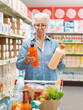 © StockPhotoPro - Senior customer comparing products at the supermarket