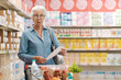© StockPhotoPro - Shocked senior customer holding a long expensive grocery receipt