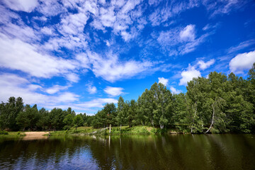 Beautiful summer river at sunny day with clouds reflection in the water