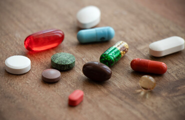 different types of pills and tablets and capsules on wooden background