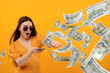 © New Africa - Excited woman throwing money on orange background. Dollar bills flying away from her
