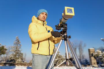 Wall Mural - amateur astronomer looking at the sun trough a telescope with special solar filter.