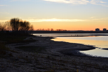 a lake with trees and a bridge in the sunset