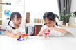 © K2L Family - two sibling Asian girl playing windmill stacks at home