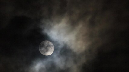 Wall Mural - The full moon shines down on the Earth at night, with occasional clouds obscuring the light.